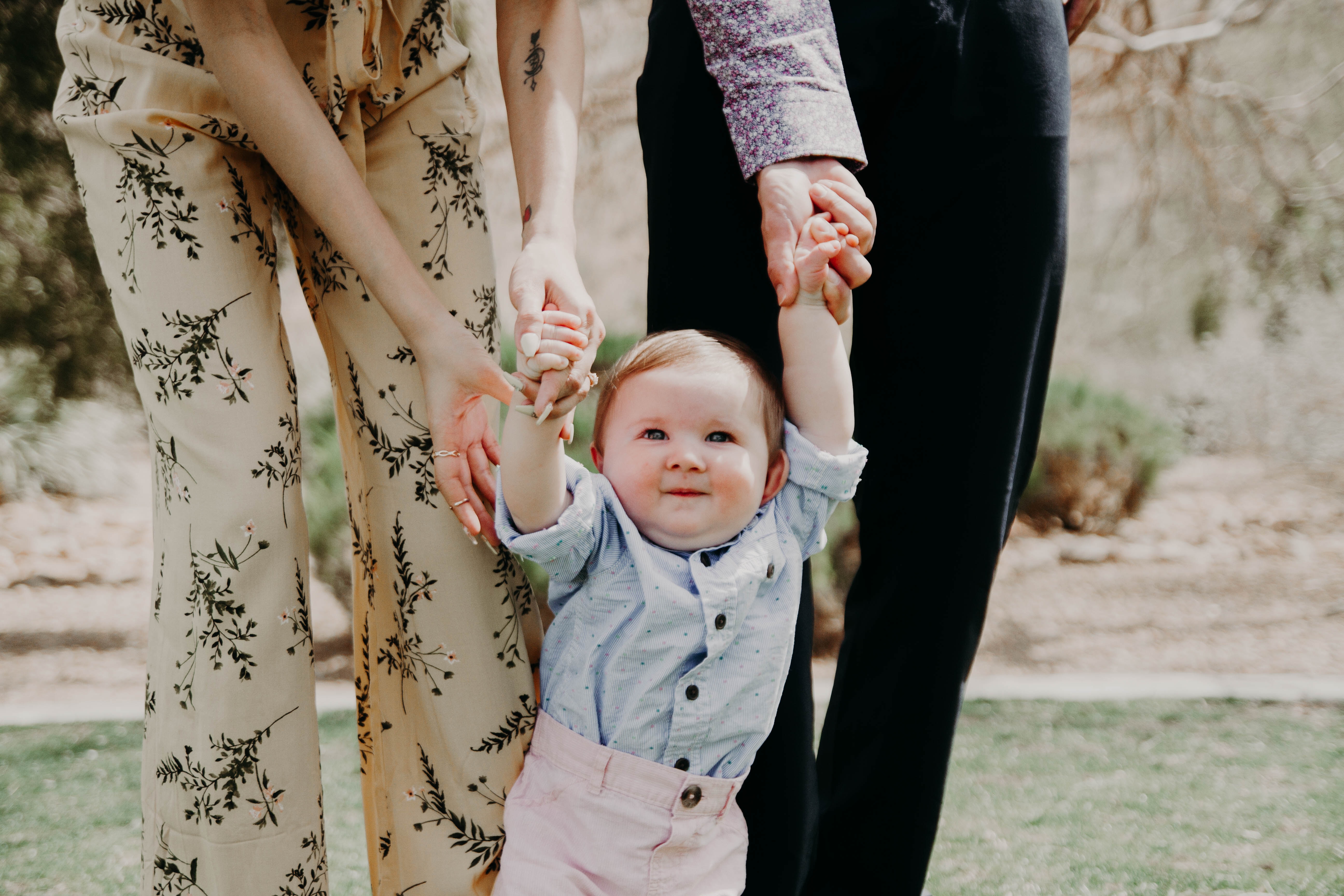 Two parents holding a childs hand and helping them walk